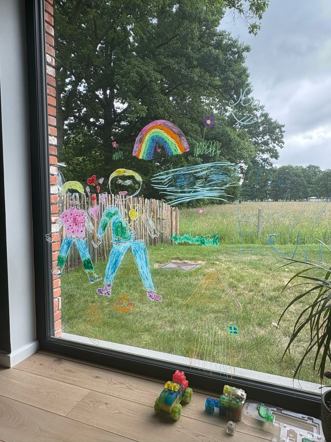 Kindertekeningen op een raam met weide uitzicht